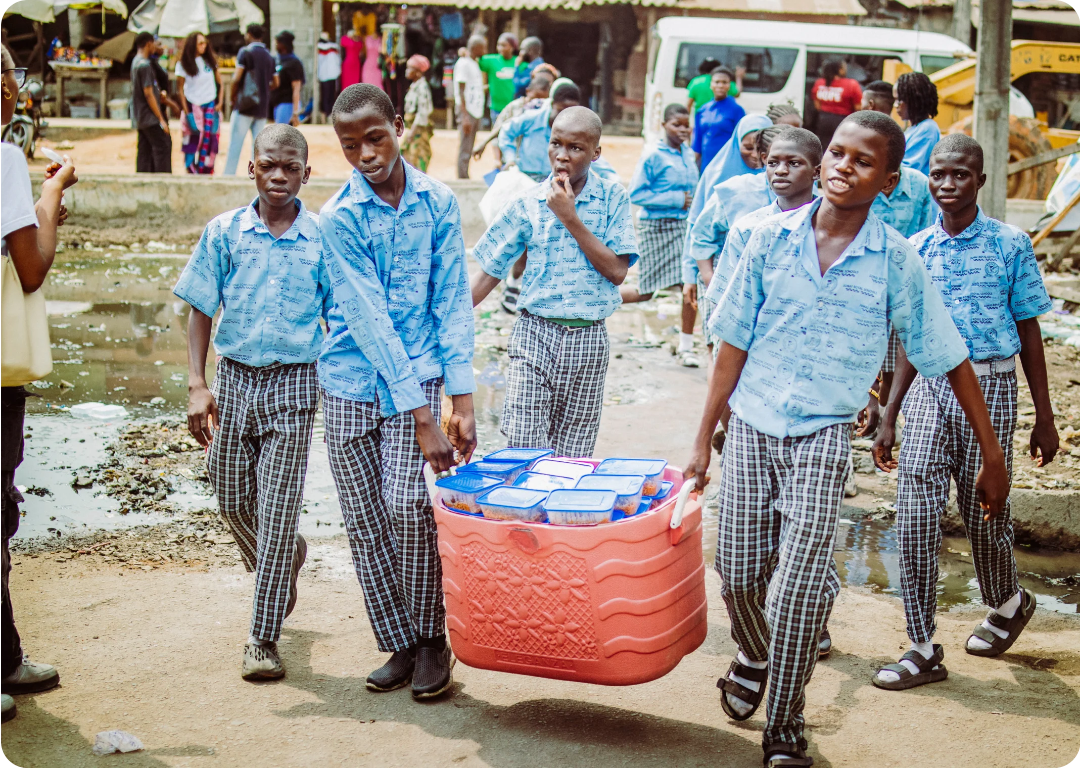 two students followed by others carrying a cooler of food